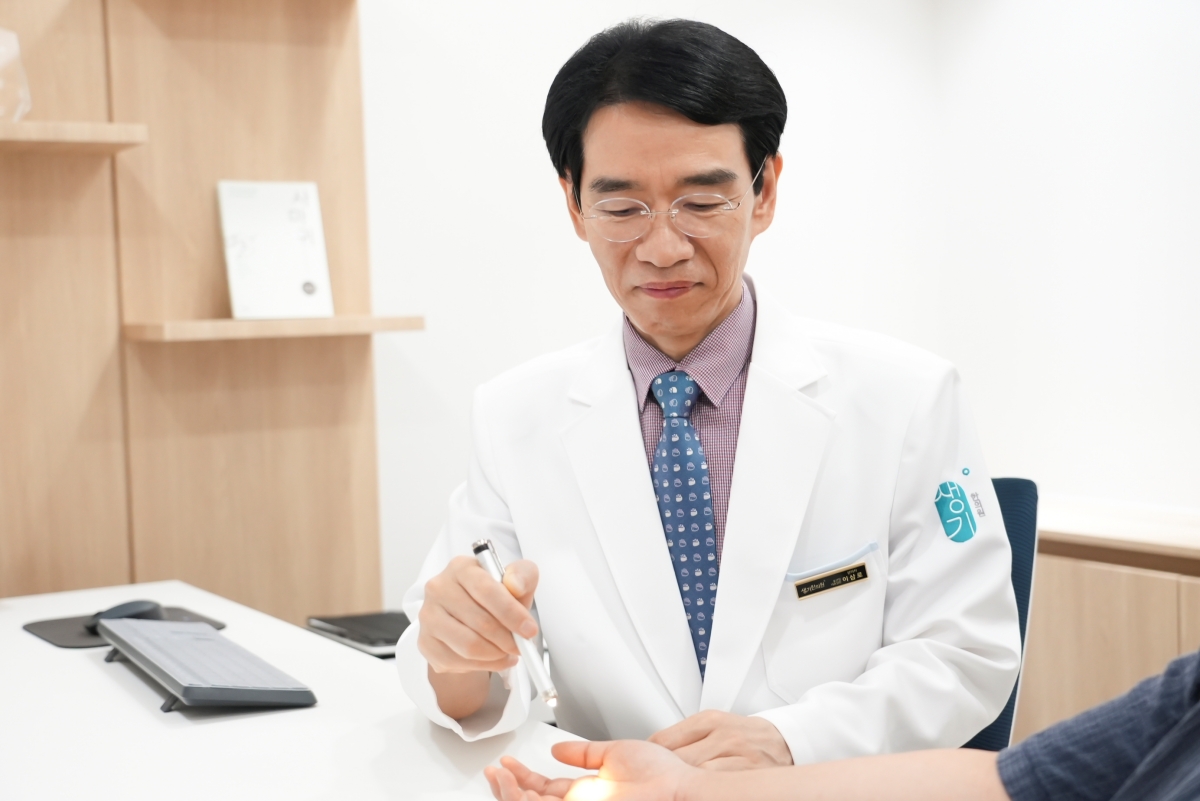 손바닥 병변을 불빛으로 비춰 가까이에서 살핍니다.
